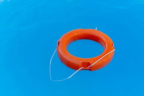 Bright orange lifebuoy floating on the surface of the water, rescuing people  Stock Photos