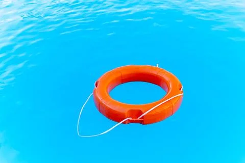 Bright orange lifebuoy floating on the surface of the water, rescuing people  Stock Photos