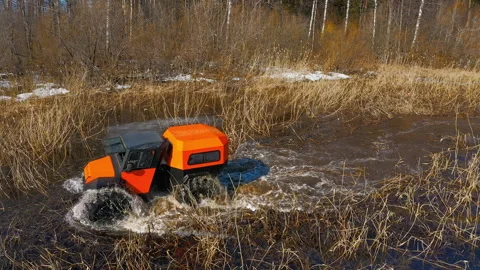 Bright orange marshmobile rides through water and dense reeds, splashing around Stock Footage 262628906