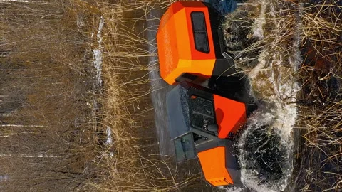 Bright orange marshmobile rides through water and dense reeds, splashing around Stock Footage 263077443