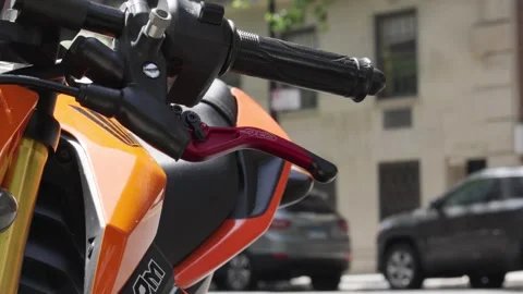 A bright orange motorcycle set of handlebars and red brake lever sit on the Stock Footage 242365950