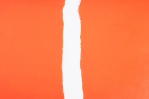 Bright orange paper with a vertical torn edge revealing a clean white space.. Фото