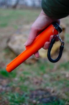 Bright orange pinpointer metal detector held in hand Foto stock