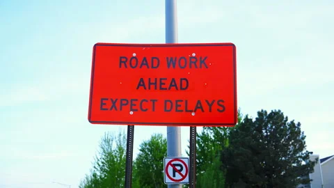 Bright orange road work sign warning drivers of construction and expected Stock Footage 334061878