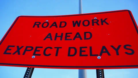 Bright orange road work sign warning drivers of construction and expected Stock Footage 334062040