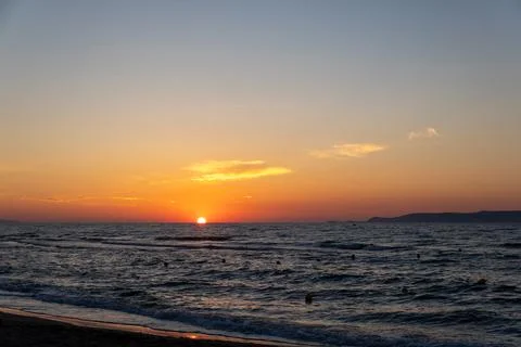 Bright orange sun setting below ocean horizon line at twilight dusk Fotos Stock