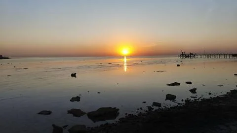 Bright orange sun setting or rising over the horizon with the sea in the Stock-Fotos