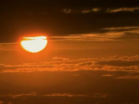 Bright Orange Sun Setting Through Clouds At Sunset Stock Photos