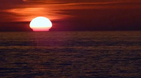 Bright orange sun sinking behind calm ocean Stock Footage 45521588