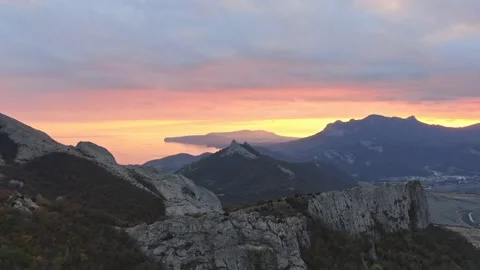 A bright orange sunset over a coastal mountain range under an overcast sky with Stock Footage 170645836