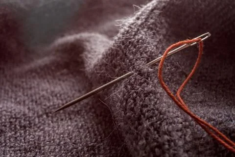 Bright orange thread and needle on fabric Stock Photos