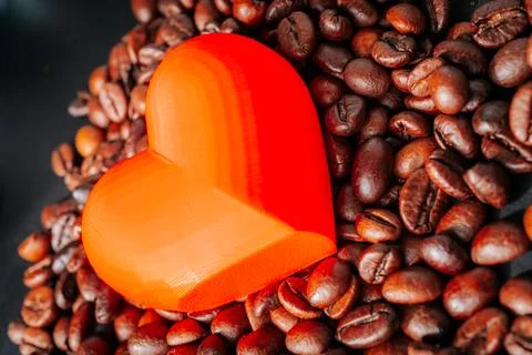 A bright orange translucent heart placed on roasted coffee beans. Stockfoto's
