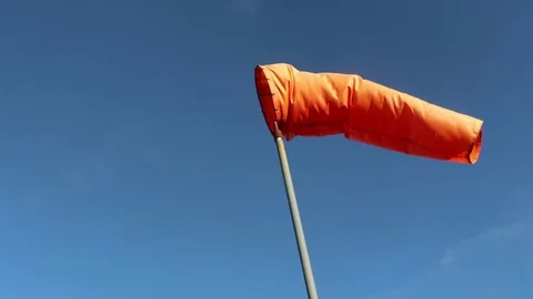 Bright Orange Windsock Swaying in a Clear Blue Sky Stock Footage 94688335