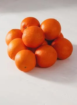 Bright oranges piled on white surface. Smooth texture with natural dimples. Stock Photos