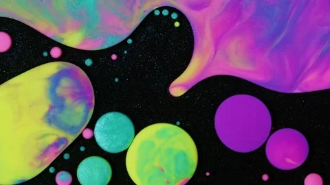 Bright paint dribbles and drops around a black surface with glitter. Biomorphic Stock Footage 242746609