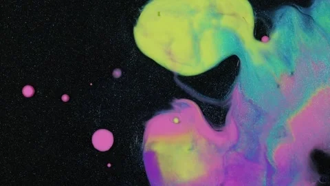 Bright paint dribbles and drops around a black surface with glitter. Biomorphic Stock Footage 255958440