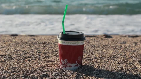 Bright paper cup of coffee on a sandy beach. Seashore Stock-Footage 60368473
