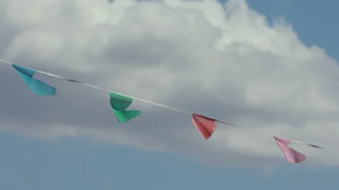 Bright party bunting flags blowing in wind under cloudy sky Stock Footage 333746285