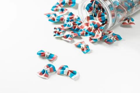 Bright paste in the form of bows spilled out of a glass jar. Stock Photos