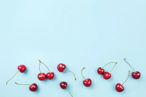 Bright pattern of ripe cherries on a blue background. Stock Photos