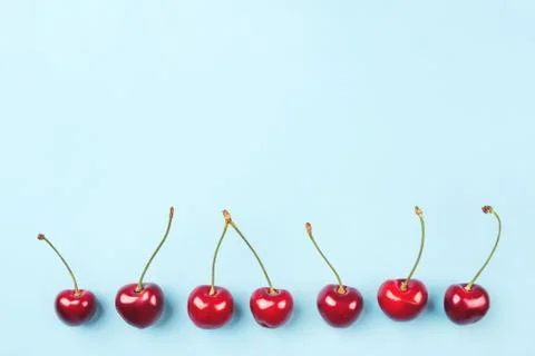 Bright pattern of ripe cherries on a blue background. Stock Photos