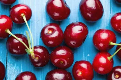Bright pattern of ripe cherries on a blue background Stock Photos