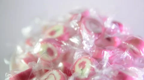 Bright pink candy in a transparent wrapper on a light background rotate slowly. Stock Footage 62978681