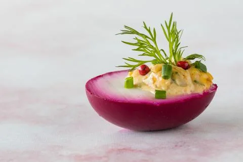 A bright pink Deviled egg garnished with chives, peppercorns and dill. Stock Photos