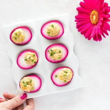 Bright pink Deviled eggs garnished with chives, ready for eating. 스톡 사진