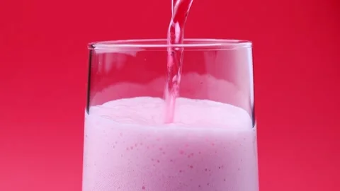 Bright pink foamy fruit cherry beer pouring down into the glass close up Stock Footage 303913248