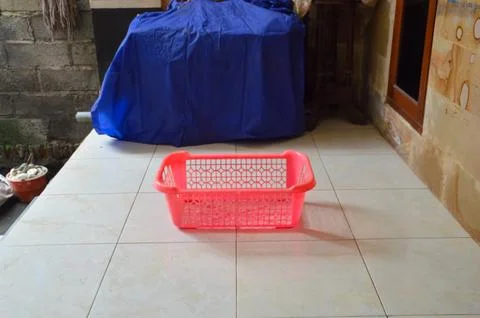 A Bright Pink Rectangular Plastic Laundry Basket Sitting On A Tiled Terrace.. 스톡 사진