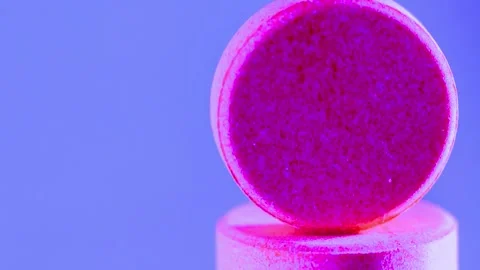 Bright pink tablets stacked vertically on vibrant purple studio background Stock-Footage 341970097