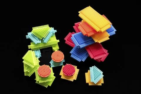 Bright plastic blocks stack high against a stark black background Foto stock