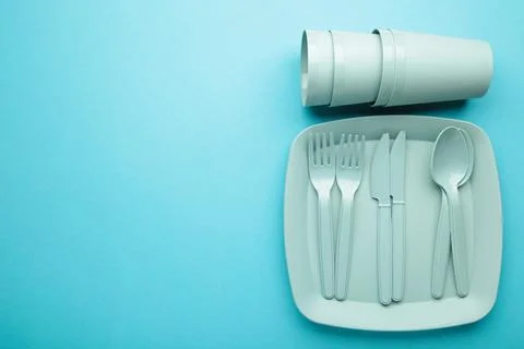 Bright plastic disposable tableware on blue background. Space for text Stock Photos