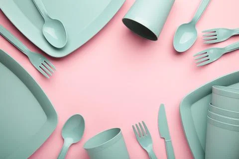Bright plastic disposable tableware on pink background. Stock Photos