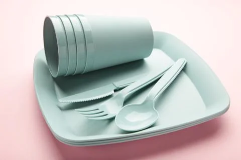 Bright plastic reusable tableware on a pink background. Stock Photos