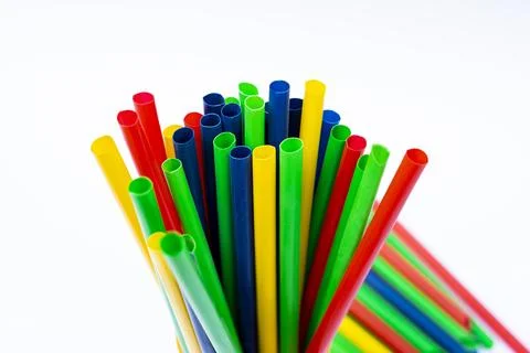 Bright plastic straws arranged vertically inside cup on plain white backdrop Stock Photos