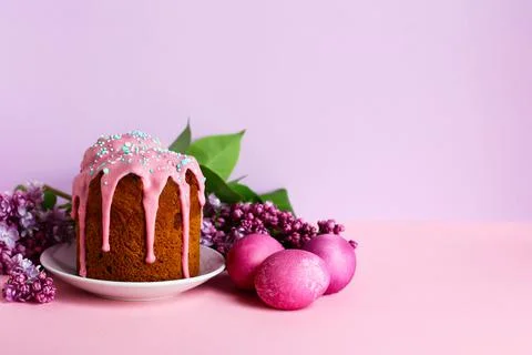 Bright purple easter eggs, cake and lilac flowers on a purple background. Eas Stock Photos