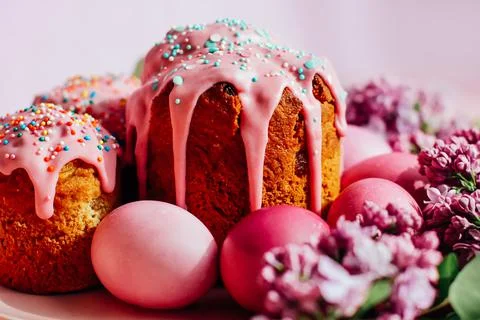 Bright purple easter eggs, cake and lilac flowers on a purple background. Eas 库存照片