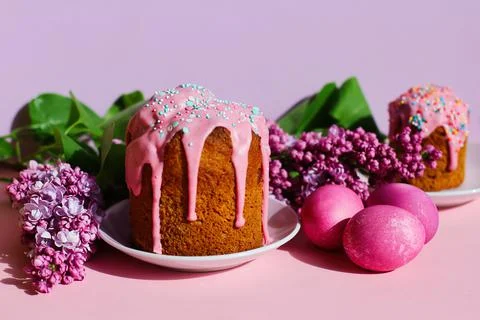 Bright purple easter eggs, cake and lilac flowers on a purple background. Eas 库存照片