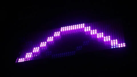 A bright purple LED digital display board showing a arrow symbol in the dark. Stock Footage 344962822