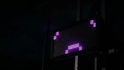 A bright purple LED digital display board showing a arrow symbol in the dark. Stock Footage 344962824