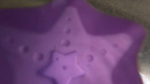 Bright purple star toy floating on the clear blue water surface. Sun reflection Stock Footage 339794063