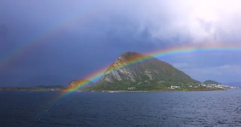 Bright rainbow arches over a lush mountain island Stock Footage 312314815