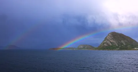 Bright rainbow arches over a lush mountain island Stock Footage 312314866