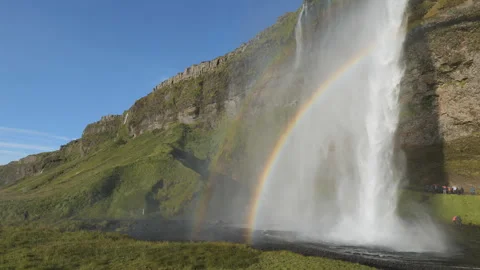 A bright rainbow arching over a large, misting waterfall. Stock Footage 335960485