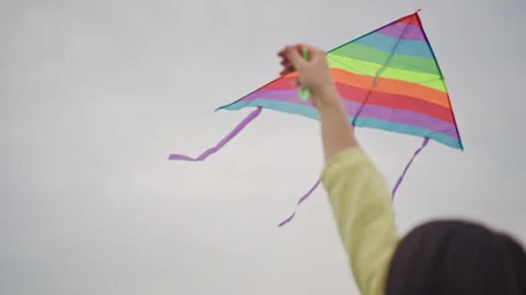Bright rainbow kite dancing through overcast sky, Closeup of lively rainbow kite Stock Footage 325331624