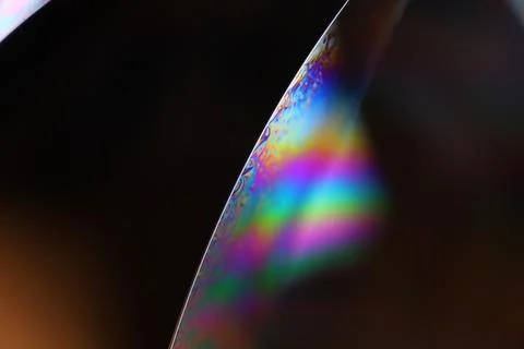 Bright rainbow reflection of liquid on black background Stock Photos