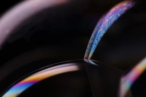 Bright rainbow reflection of liquid on black background Stock Photos