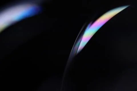 Bright rainbow reflection of liquid on black background Stock Photos